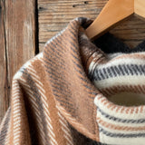 Klasiskas rūtis karameļi brūnos/pelēkos/baltos toņos indiāņu piegriezuma garais aitas vilnas pončo ar kapuci un bārkstīm